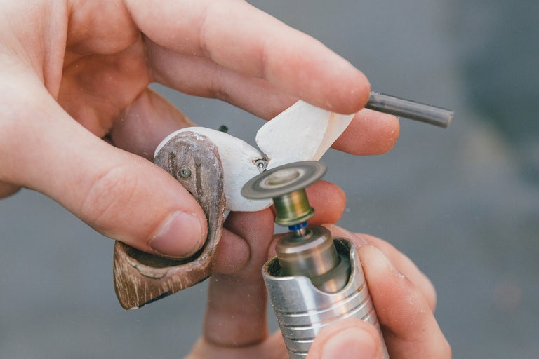 Nahaufnahme von Händen, die ein Holzkunstwerk mit einem rotierenden Werkzeug bearbeiten