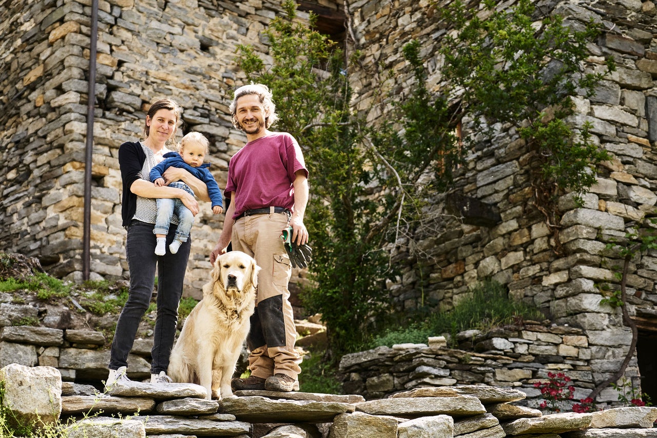 Familie mit Hund vor einem Haus aus Stein.