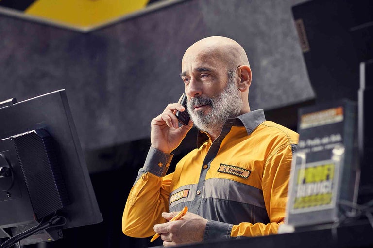 Ein Mitarbeiter von Hornbach telefoniert und hält einen Stift in der Hand.