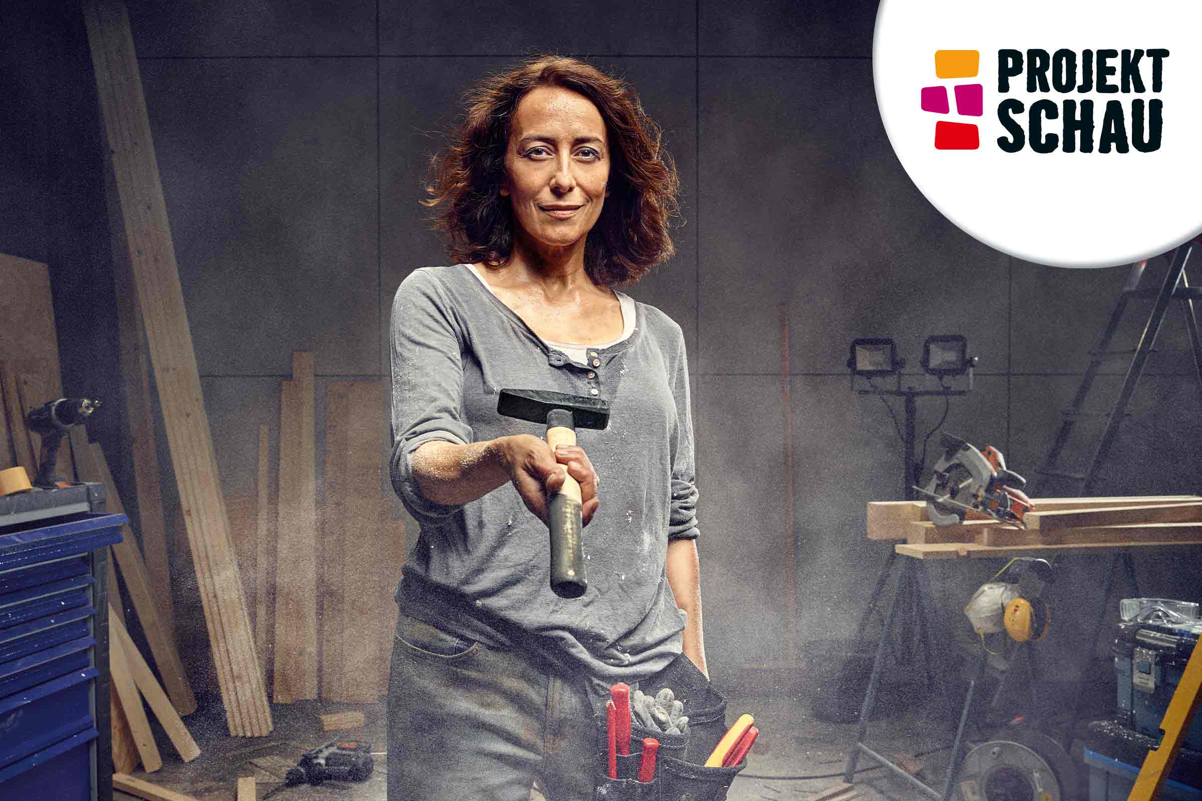 Frau hält Hammer in der Werkstatt, im Hintergrund Holz und Werkzeuge, Projekt Schau Logo
