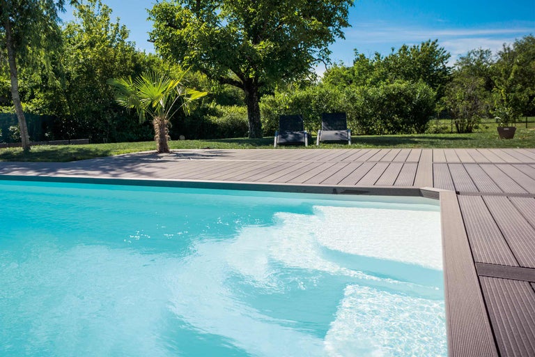 Szene mit einem Pool, Holzdeck und zwei Gartenliegen im Hintergrund