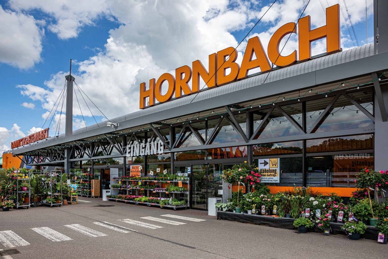 Außenansicht eines Hornbach Baumarkts mit Pflanzen vor dem Eingang