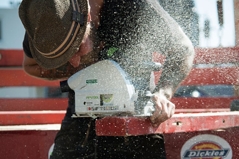 Handwerker sägt Holz mit einer Handkreissäge von Festool, Sägespäne fliegen in der Luft.