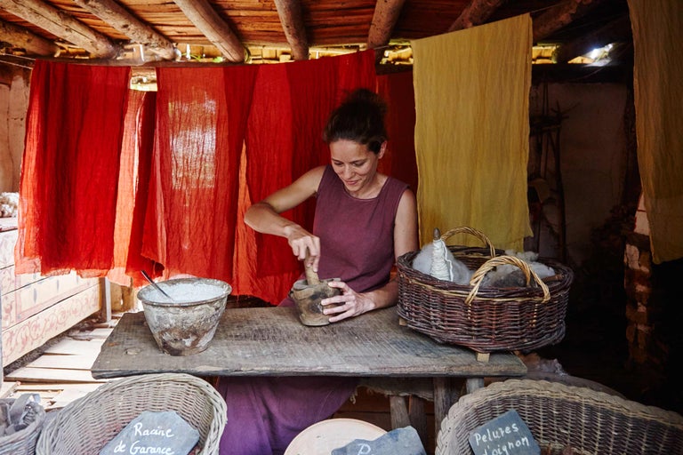 Eine Frau arbeitet in einem Marktstand mit Werkzeugen und Zutaten zum Färben von Wolle.