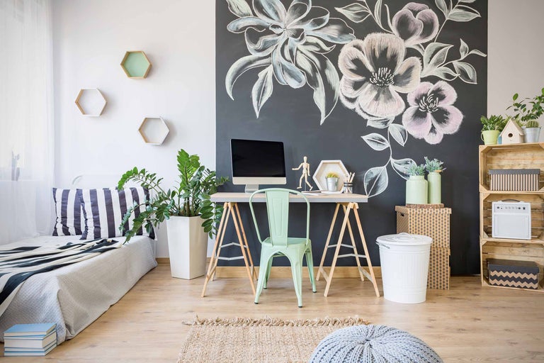 Büro mit Schreibtisch, Stuhl, Wandtafel mit Blumenzeichnung und dekorativen Elementen