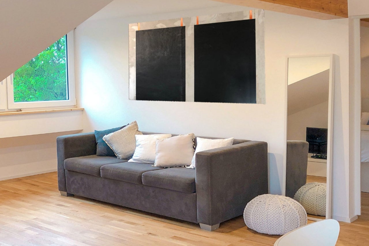 Wohnzimmer mit Sofa, Kissen, Spiegel und Dekoration