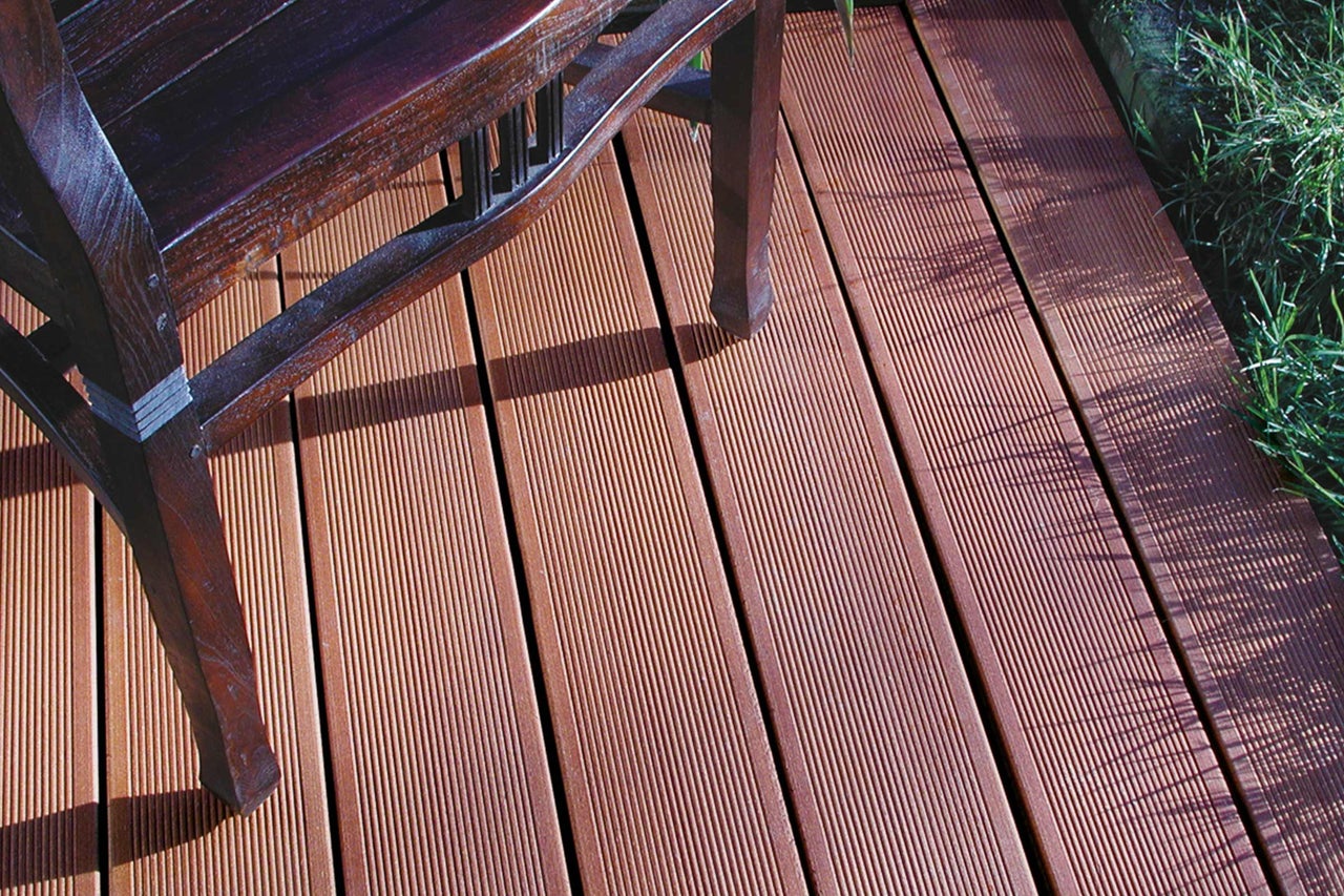 Terrassendielen aus Holz mit gerillter Oberfläche und einem Stuhlbein im Bild.