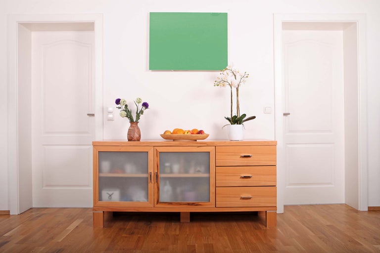 Wohnzimmer mit Kommode aus Holz, zwei Türen und einem grünen Bild
