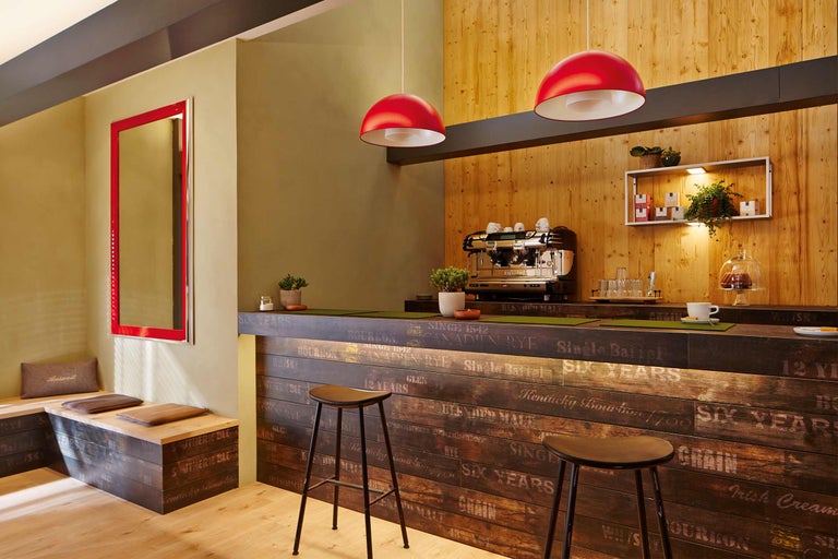 Gastraum mit Bar aus Holz, Barhockern und roter Beleuchtung