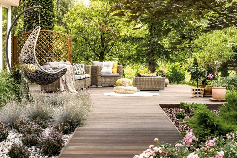 Gartenlounge-Set mit Hängesessel auf einer Holzterrasse im Grünen