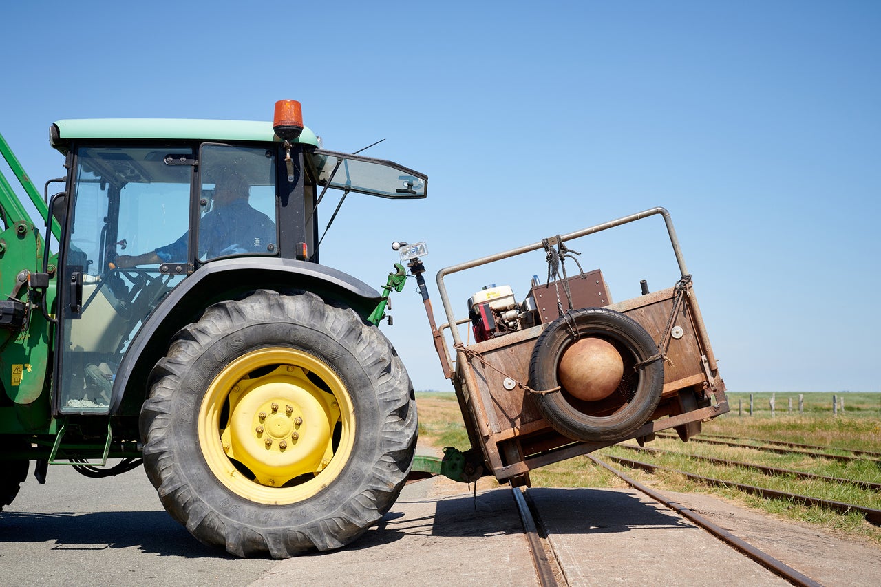 Traktor mit angehängtem Wagen auf Schienen