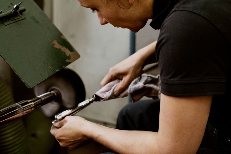 Eine Person poliert mit einem Tuch ein Metallprodukt an einer Poliermaschine.