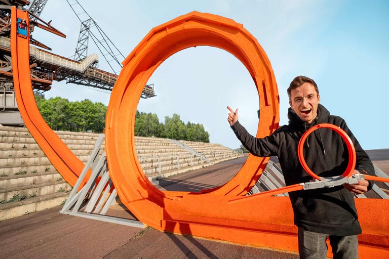 Mann mit Hot Wheels Rennbahn Loop vor Industriekulisse