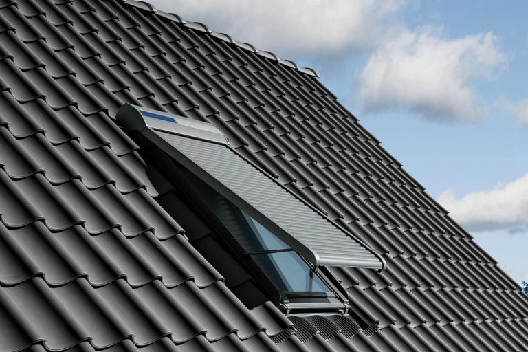 Dachfenster mit Rollladen auf einem Dach mit Dachziegeln