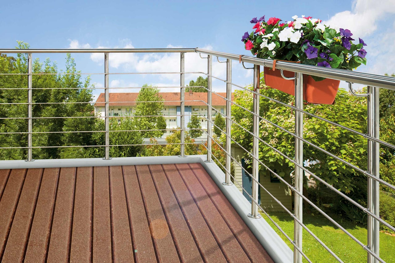 Balkon mit braunem Holzboden und Edelstahlgeländer sowie Blumenkasten