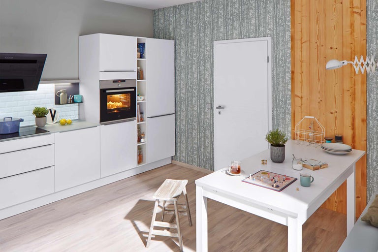 Heller Küchenbereich mit weißen Möbeln, Esstisch und Stuhl.