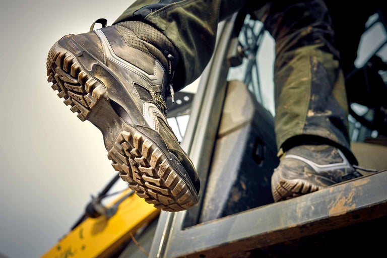 Detailaufnahme eines schmutzigen Arbeitsschuhs mit grobem Profil