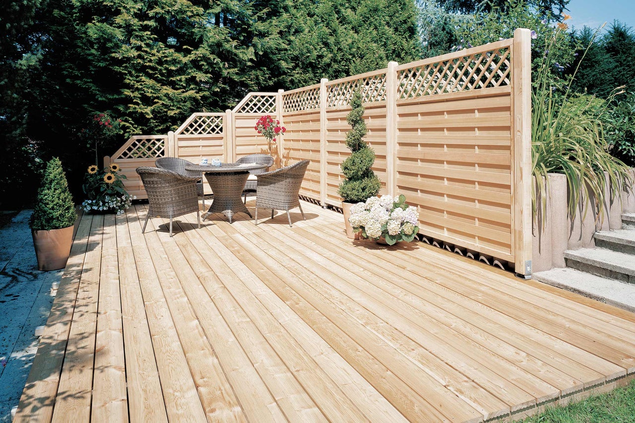 Holzterrasse mit Sichtschutzzaun und Gartenmöbeln im Garten.