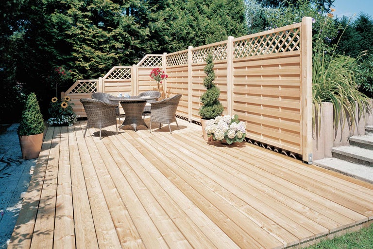 Holzterrasse mit Sichtschutzzaun und Gartenmöbeln im Garten.