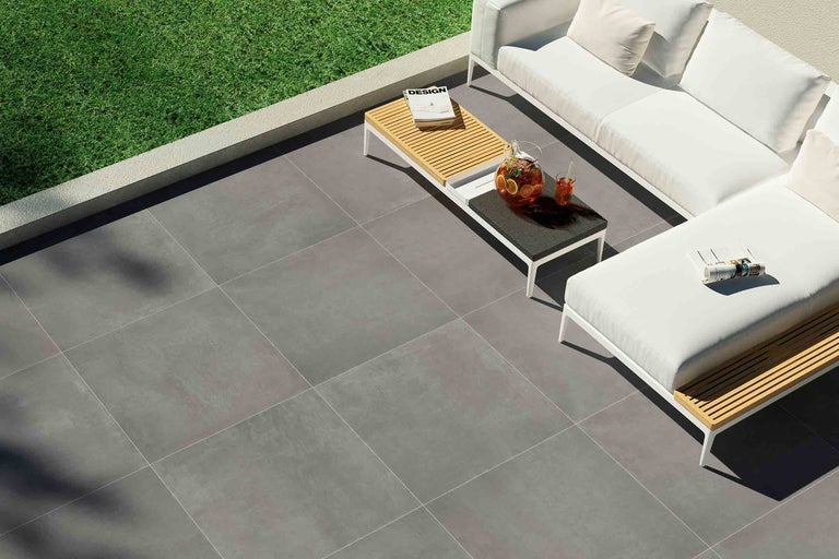 Terrasse mit grauen Bodenfliesen und weißen Gartenmöbeln