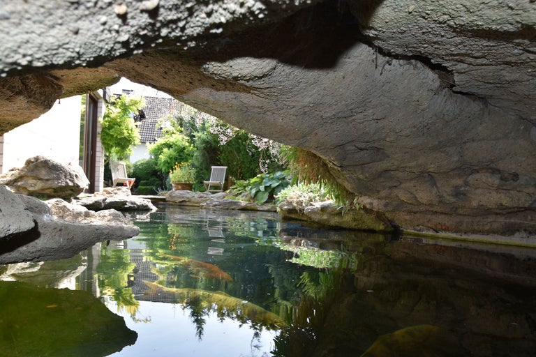 Teich mit Felsen und Gartenmöbeln im Hintergrund
