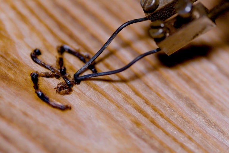 Detailaufnahme eines Brennstempels beim Verzieren von Holz