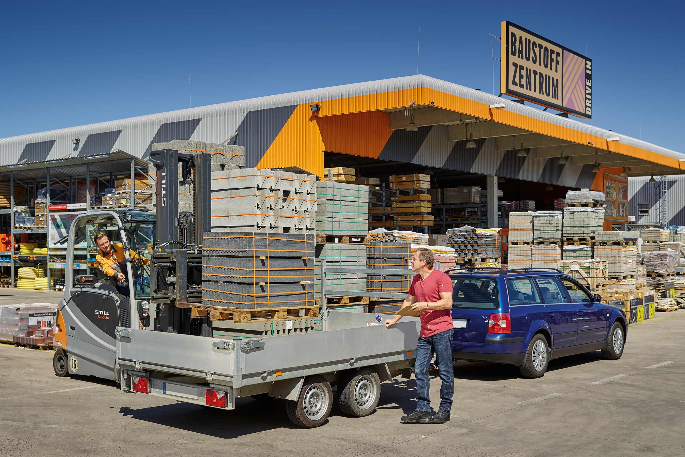 Ein Mann belädt einen Anhänger mit Pflastersteinen vor dem Hornbach Baustoffzentrum.