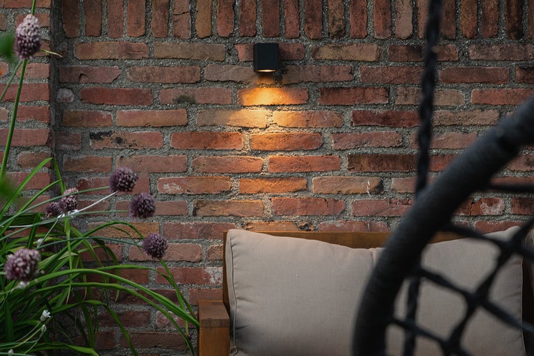 Eine Gartenmauer mit einer Außenleuchte, die eine gemütliche Atmosphäre schafft.