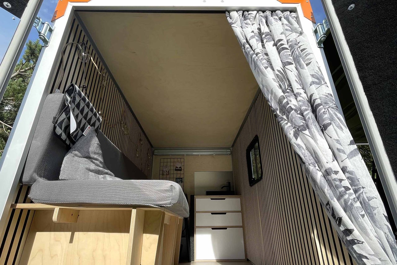 Innenausbau eines Lieferwagens mit Bett, Vorhängen und Stauraum