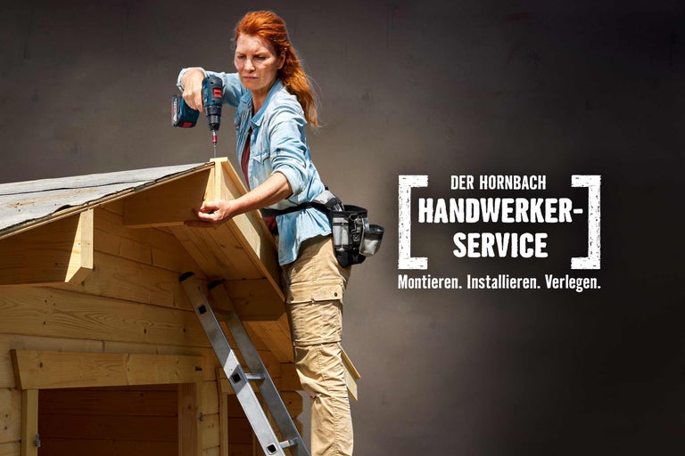 Frau mit Akkuschrauber bei Holzarbeiten am Dach eines Holzhauses, Hornbach Handwerkerservice