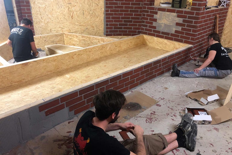 Personen verlegen Ziegelriemchen auf eine Holzkonstruktion