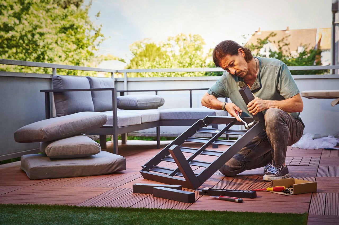Mann baut Gartenmöbel zusammen.