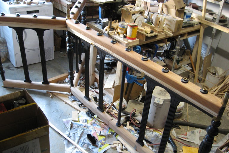 Unfertiges Holzgeländer mit schwarzen Geländerstäben in einer Werkstatt.