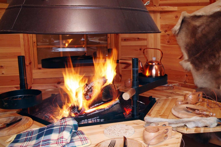 Gemütlicher Innenraum mit offenem Feuer, Kochstelle und Holztisch mit Geschirr