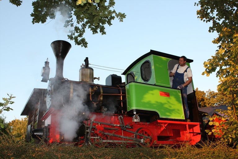 Eine Dampflokomotive mit einem Mann im Führerhaus.