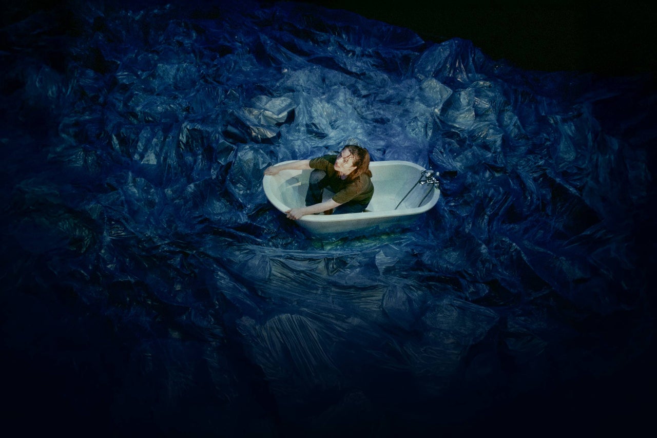 Frau sitzt in Badewanne inmitten von Wasser.
