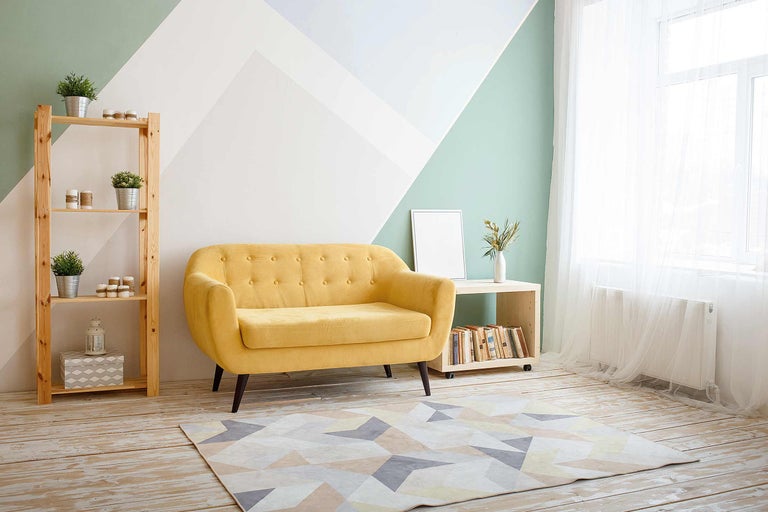 Helles Wohnzimmer mit gelbem Sofa, Holzregal und geometrischem Teppich