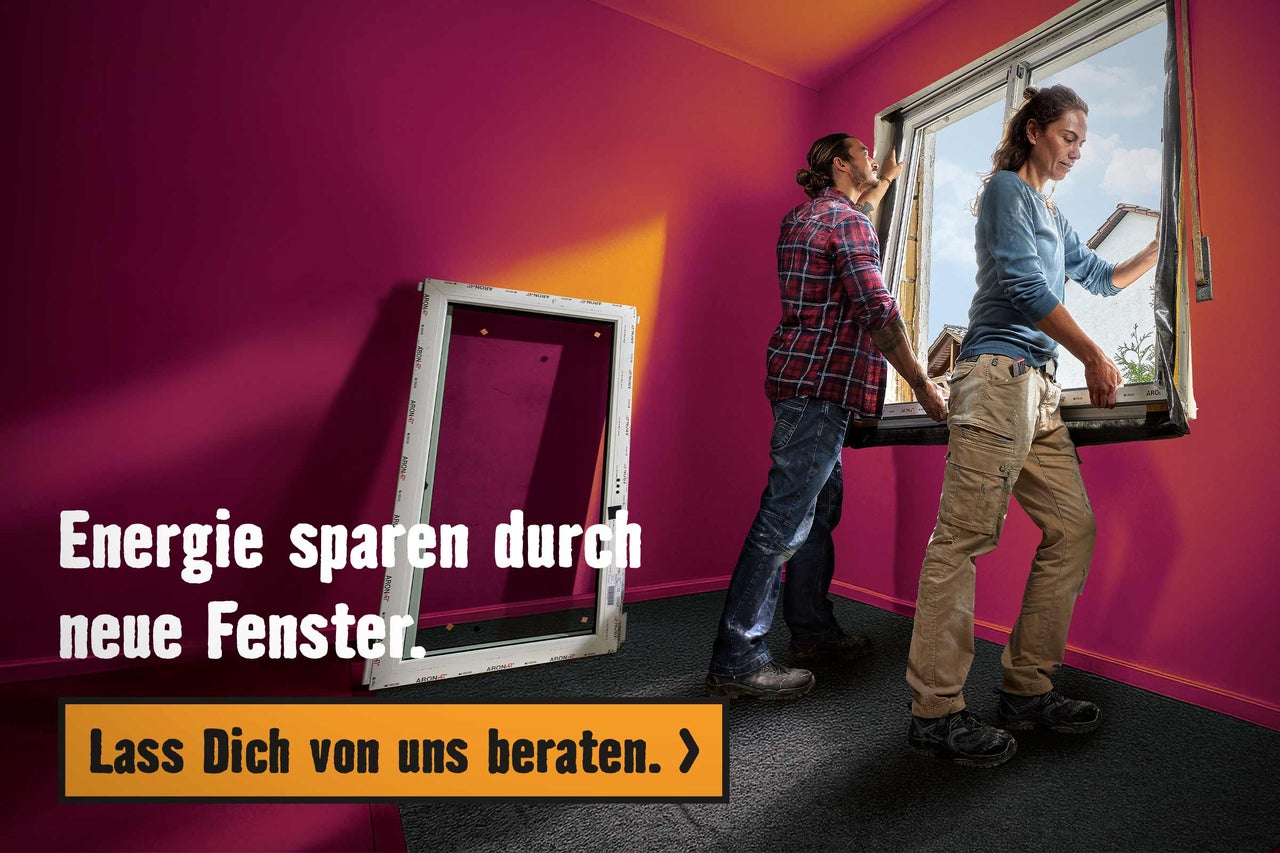 Zwei Personen bauen ein neues Fenster ein. Ein weiteres Fenster steht im Raum.