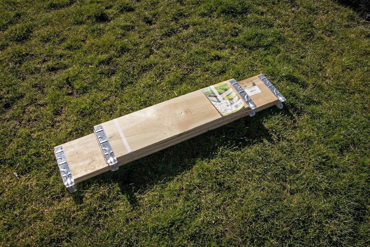 Holzbohlenpaket mit Metallverbindern auf Gras
