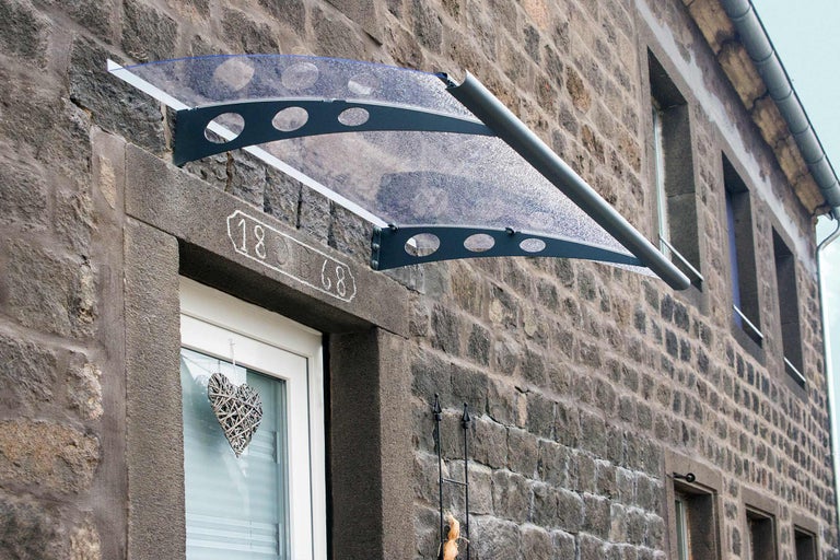 Vordach aus Polycarbonat an einer Hauswand aus Stein