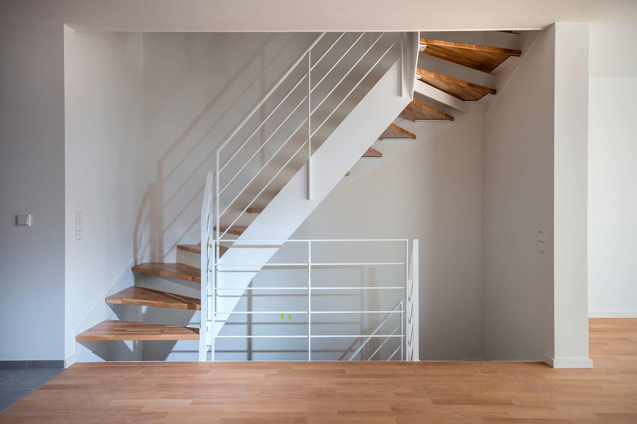 Treppe mit Holzstufen und weißem Geländer in einem hellen Raum