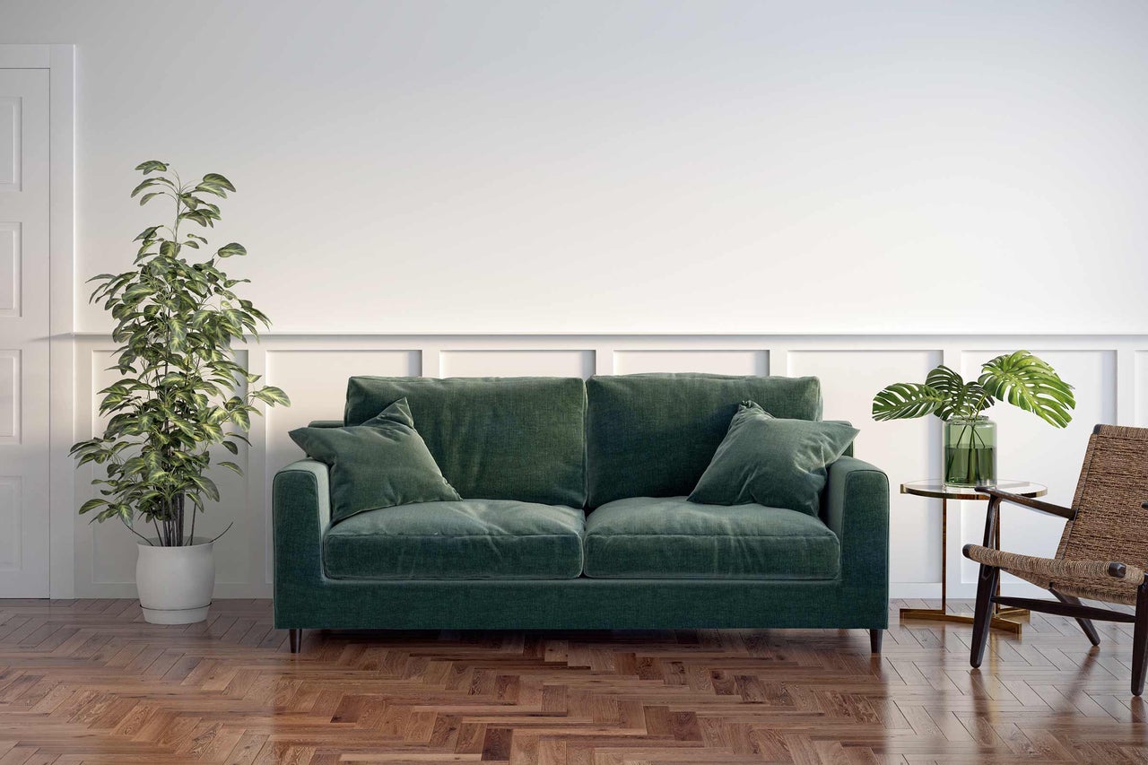 Gemütliches Wohnzimmer mit grünem Sofa, Zimmerpflanzen und Holzboden
