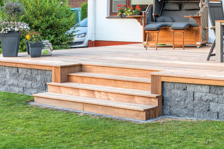 Terrasse mit Holzstufen, Mauer und Strandkorb im Garten