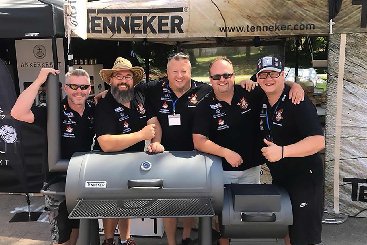 Gruppe von Personen vor einem Tenneker Grill bei einer Veranstaltung.