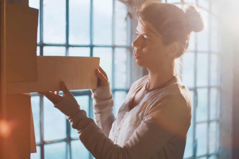Frau hantiert mit Holzplatten vor einem Fenster. Heimwerken.