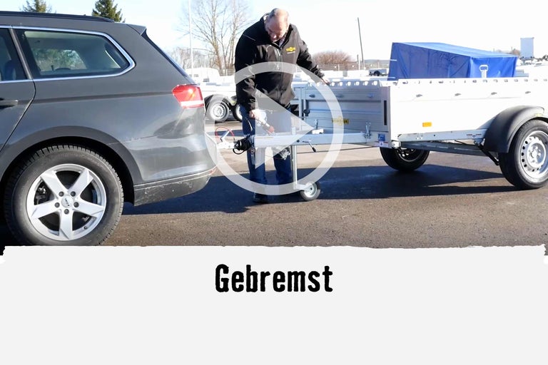 Video: Eine Person kuppelt einen Autoanhänger an ein Auto an.