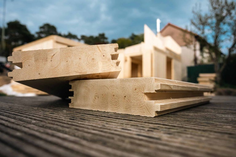 Massivholzbohlen mit Nut und Feder Profil für den Aufbau eines Gartenhauses im Außenbereich.
