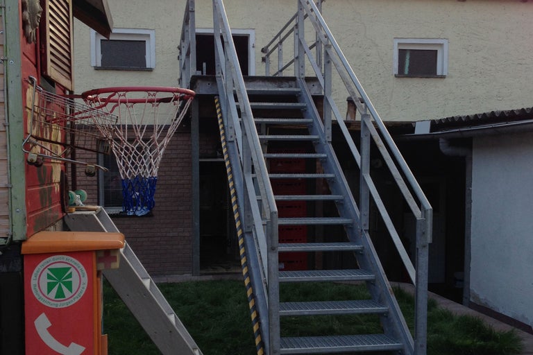 Außenansicht eines Gebäudes mit Treppe und Basketballkorb