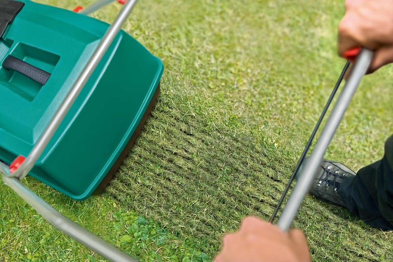 Ein Rasenlüfter wird über einen Rasen geschoben, wodurch dieser belüftet wird.