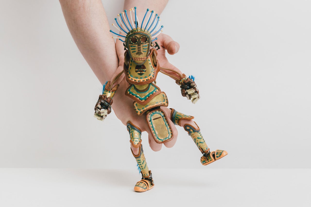 Hand hält eine Marionette mit Federschmuck
